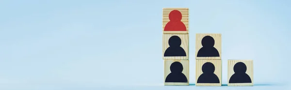 Pyramide de blocs de bois avec des icônes humaines noires et rouges sur fond bleu, concept de leadership, vue panoramique — Photo de stock