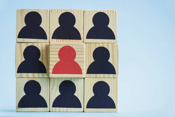 Квадрат деревянных блоков с черно-красными человеческими иконами на синем фоне, концепция лидерства — стоковое фото
