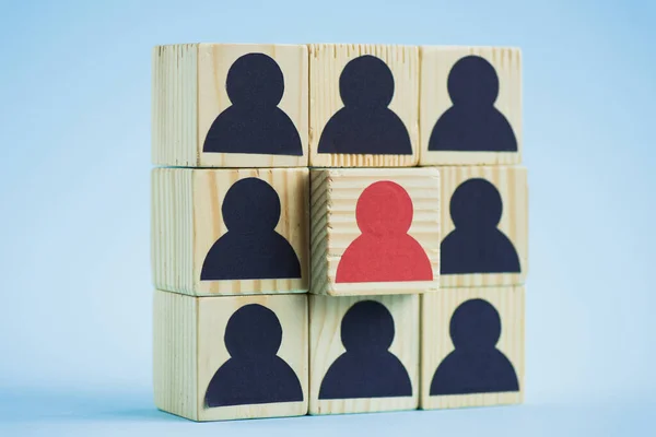 Square of wooden blocks with black and red human icons on blue background, leadership concept — Stock Photo