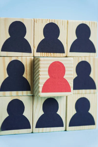Cuadrado de bloques de madera con iconos humanos negros y rojos sobre fondo azul, concepto de liderazgo - foto de stock