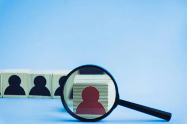 Selective focus of magnifying glass near wooden block with red human icon on blue background, leadership concept — Stock Photo