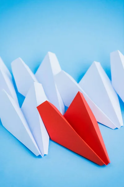 Planos de papel blanco y rojo sobre fondo azul, concepto de liderazgo - foto de stock