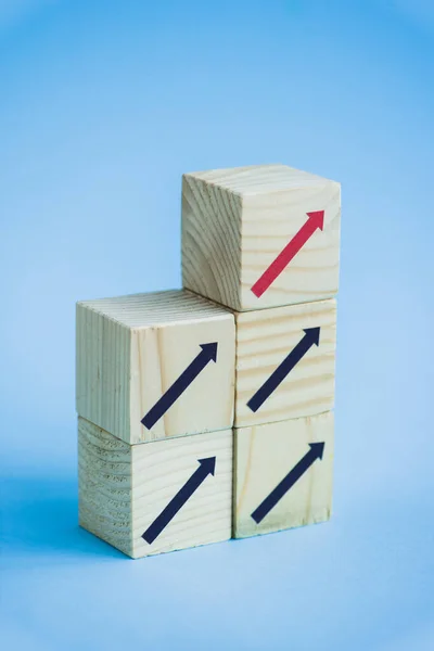 Bloques de madera con flechas negras y rojas sobre fondo azul, concepto de liderazgo - foto de stock