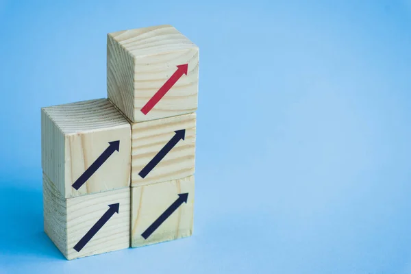 Bloques de madera con flechas negras y rojas sobre fondo azul, concepto de liderazgo - foto de stock