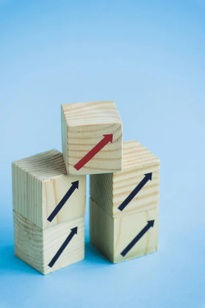 Bloques de madera con flechas negras y rojas sobre fondo azul, concepto de liderazgo - foto de stock