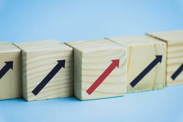 Vue rapprochée des blocs de bois avec des flèches noires et rouges sur fond bleu, concept de leadership — Photo de stock