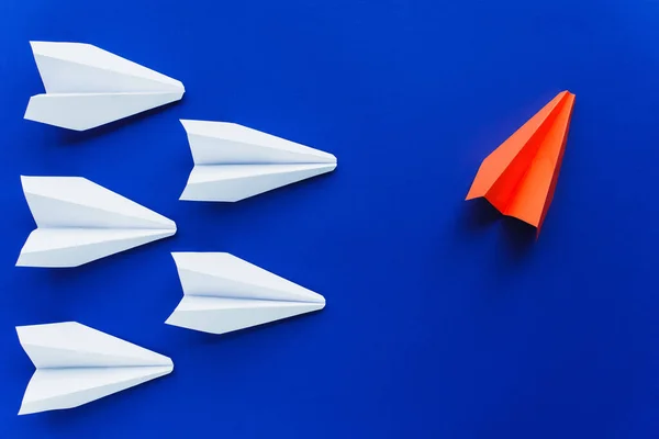 Visão superior de aviões de papel branco e vermelho em fundo azul, conceito de liderança — Fotografia de Stock