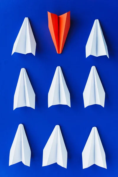 Pose plate avec des avions en papier blanc et rouge sur fond bleu, concept de leadership — Photo de stock