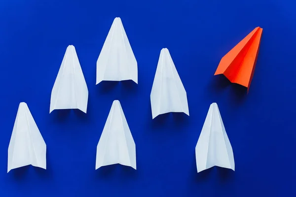 Visão superior de aviões de papel branco e vermelho em fundo azul, conceito de liderança — Fotografia de Stock