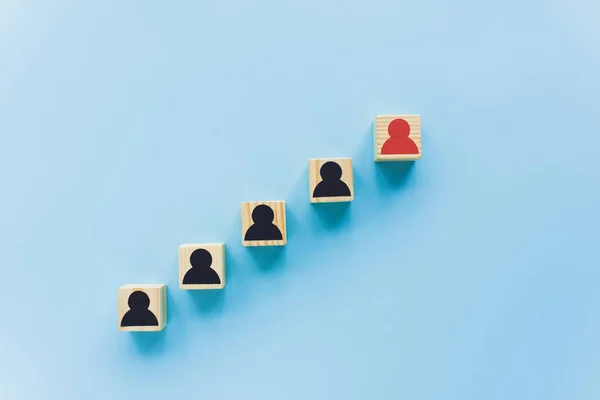 Top view of wooden blocks with black and red human icons on blue background, leadership concept — Stock Photo