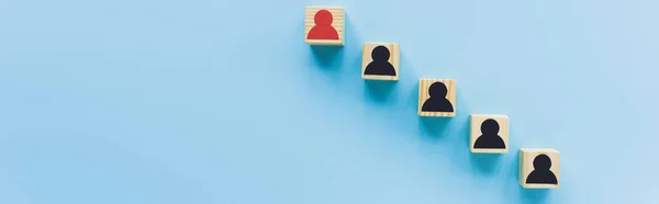 Top view of wooden blocks with black and red human icons on blue background, leadership concept, panoramic shot — Stock Photo