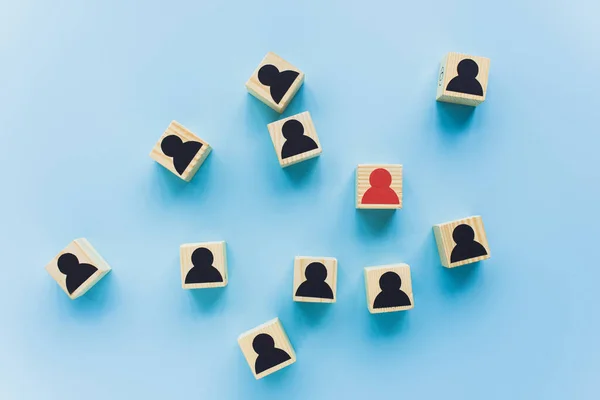 Top view of wooden blocks with black and red human icons scattered on blue background, leadership concept — Stock Photo