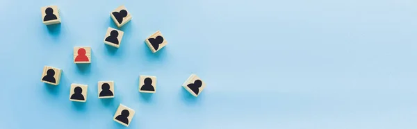 Top view of wooden blocks with black and red human icons scattered on blue background, leadership concept, panoramic shot — Stock Photo