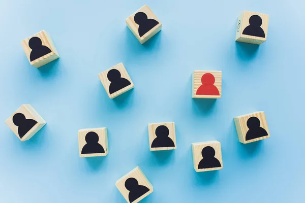 Top view of wooden blocks with black and red human icons scattered on blue background, leadership concept — Stock Photo