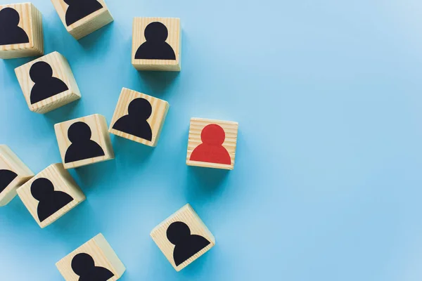 Top view of wooden blocks with black and red human icons scattered on blue background, leadership concept — Stock Photo