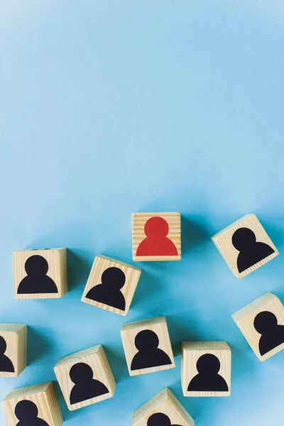 Top view of wooden blocks with black and red human icons scattered on blue background, leadership concept — Stock Photo