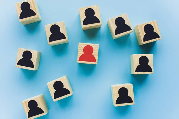 Top view of wooden blocks with black and red human icons scattered on blue background, leadership concept — Stock Photo