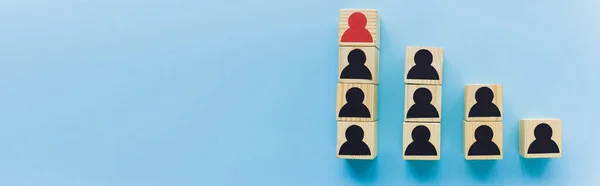 Panoramic shot of wooden blocks with black and red human icons on blue background, leadership and career ladder concept — Stock Photo