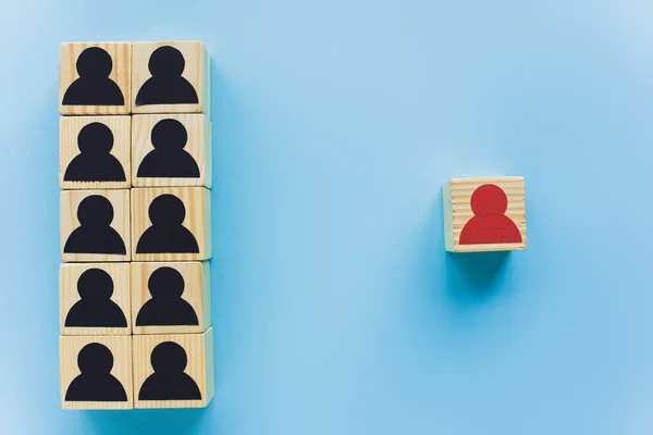 Vista dall'alto di blocchi di legno con icone umane nere e rosse su sfondo blu, concetto di leadership — Foto stock