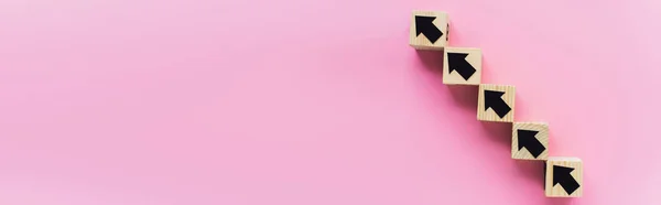 Panoramaaufnahme von Holzklötzen mit schwarzen Pfeilen auf rosa Hintergrund, Geschäftskonzept — Stockfoto