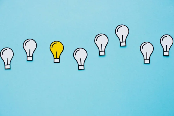 Top view of paper light bulbs on blue background, business concept — Stock Photo