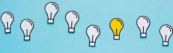 Panoramic shot of paper light bulbs on blue background, business concept — Stock Photo