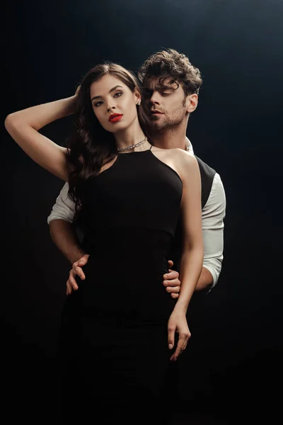Handsome man embracing sexy woman with red lips on black background — Stock Photo