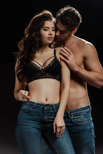 Shirtless man embracing sensual girlfriend in bra isolated on black — Stock Photo