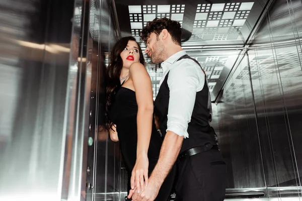 Foco seletivo de homem bonito tocando mulher bonita no elevador — Fotografia de Stock