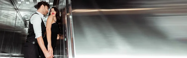 Orientación panorámica de hombre guapo tocando a mujer sexy en ascensor - foto de stock
