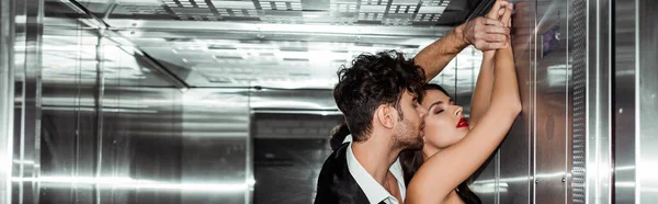Horizontal crop of young man kissing beautiful girlfriend in elevator — Stock Photo