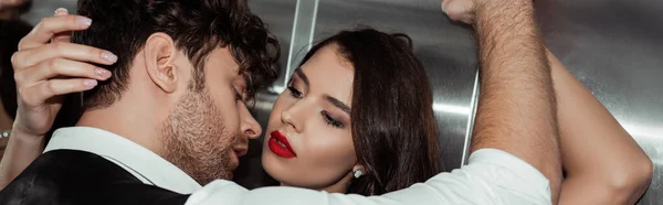 Panoramic shot of handsome man near beautiful woman with red lips in elevator — Stock Photo