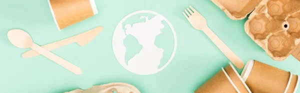 Panoramic shot of disposable tableware and paper earth sign on green background, ecology concept — Stock Photo