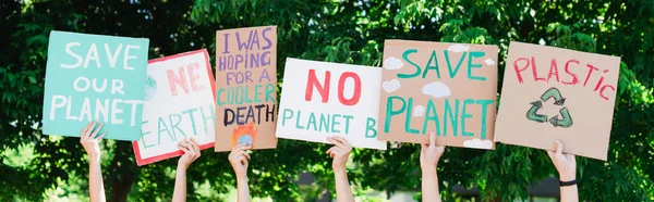 Foto panorámica de personas sosteniendo pancartas con salvar nuestro planeta y una tierra escribiendo al aire libre, concepto de ecología - foto de stock