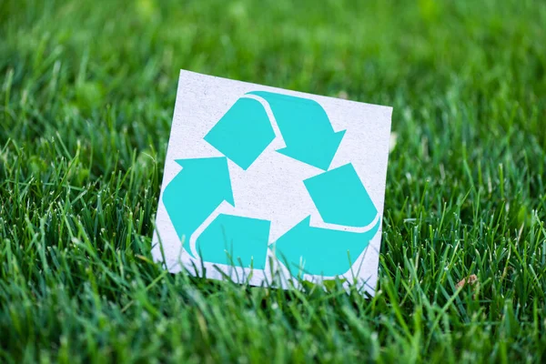 Foco seletivo do cartão com sinal de reciclagem na grama ao ar livre, conceito de ecologia — Fotografia de Stock