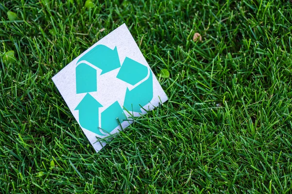 High angle view of card with recycle symbol on green grass outdoors, ecology concept — Stock Photo