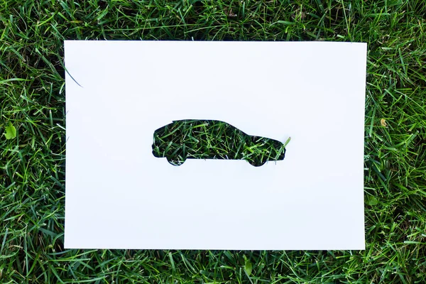 Visão superior do papel com sinal de carro na grama verde, conceito de ecologia — Fotografia de Stock