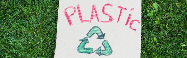 Coltivazione orizzontale di lettering plastica e riciclare segno su cartello su erba verde all'aperto, concetto di ecologia — Foto stock