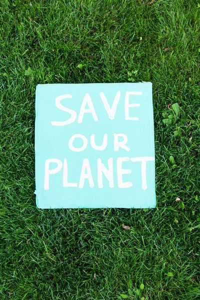Draufsicht auf Plakat mit Rettet unseren Planeten Schriftzug auf Gras, Ökologiekonzept — Stockfoto
