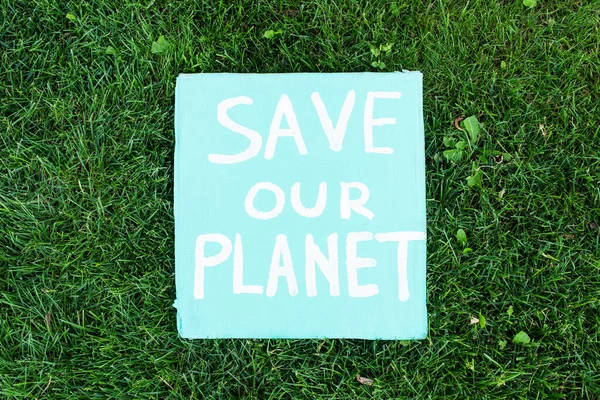 Top view of save our planet lettering on poster on green grass, ecology concept - foto de stock