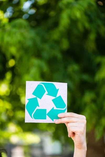 Vue recadrée de l'homme tenant la carte avec panneau de recyclage à l'extérieur, concept d'écologie — Photo de stock