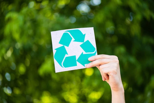 Vista recortada de la tarjeta de retención de hombre con signo de reciclaje en la mano al aire libre, concepto de ecología - foto de stock