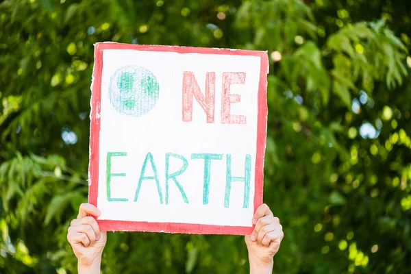 Vista cortada do homem segurando cartaz com uma terra lettering com árvores no fundo, conceito de ecologia — Fotografia de Stock