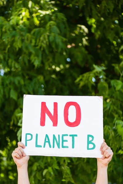 Vista recortada del hombre sosteniendo pancarta sin letras planeta b en las manos con árboles en el fondo, concepto de ecología — Stock Photo