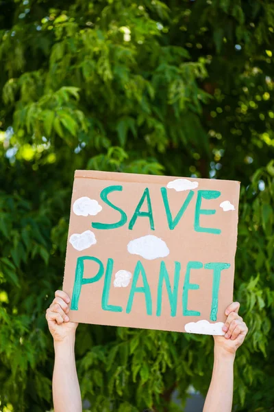 Vista recortada del hombre sosteniendo pancarta con palabras guardar planeta con árboles en el fondo, concepto de ecología - foto de stock