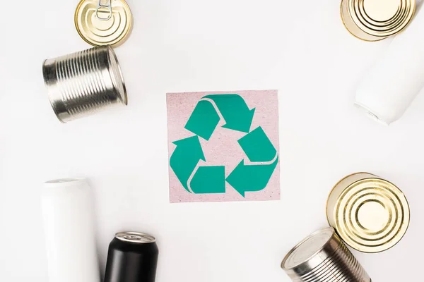 Vista superior de la tarjeta con cartel de reciclaje cerca de latas sobre fondo blanco, concepto de ecología - foto de stock