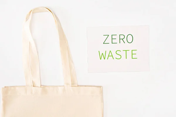 Top view of bag near card with zero waste lettering on white background, ecology concept — Stock Photo