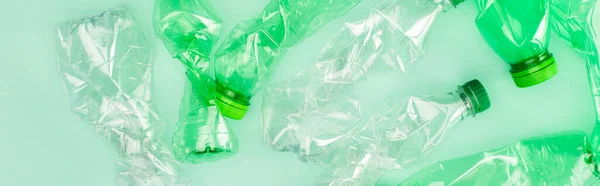 Horizontal crop of crumpled plastic bottles on green surface, ecology concept — Stock Photo