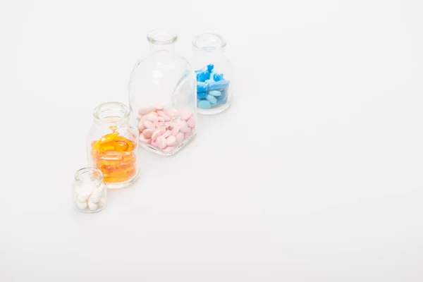 Colorful pills in glass bottles on white background — Stock Photo