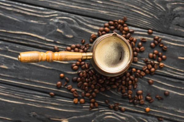 Vista superior del cezve con café en granos de café en la superficie de madera - foto de stock